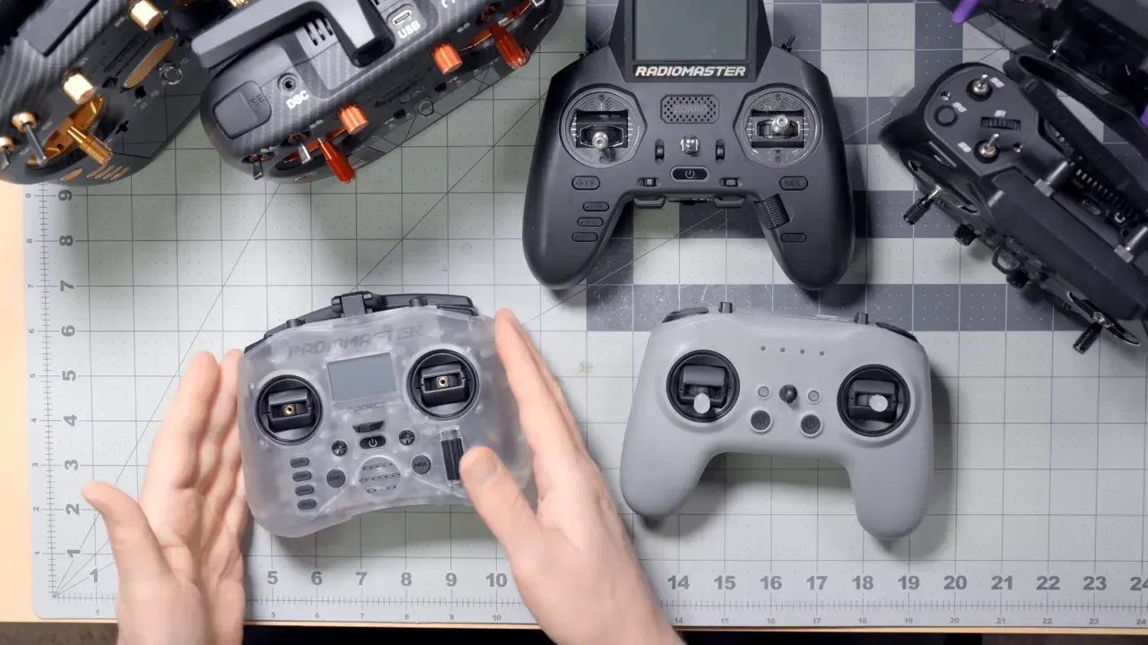 Top-down view of multiple Radiomaster radios on a cutting-mat — translucent Pocket radio at left, grey T8L-style controller at right, larger controllers above, with hands arranging them