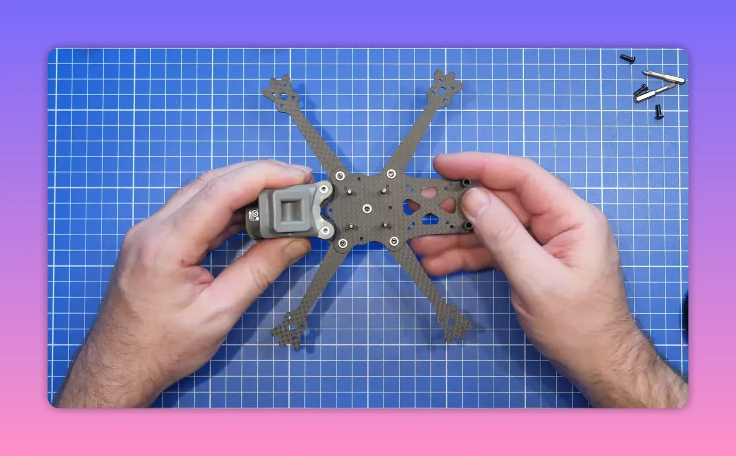 Hands fitting the ERA Mini front stack hardware onto the frame with standoffs in place on a blue cutting mat