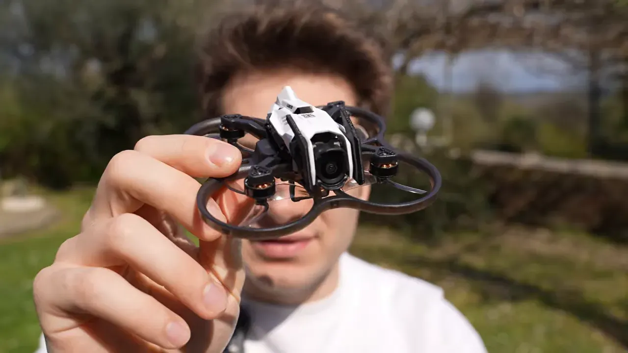Close-up of the Oxbot Lumo18 tinywhoop held by hand outdoors