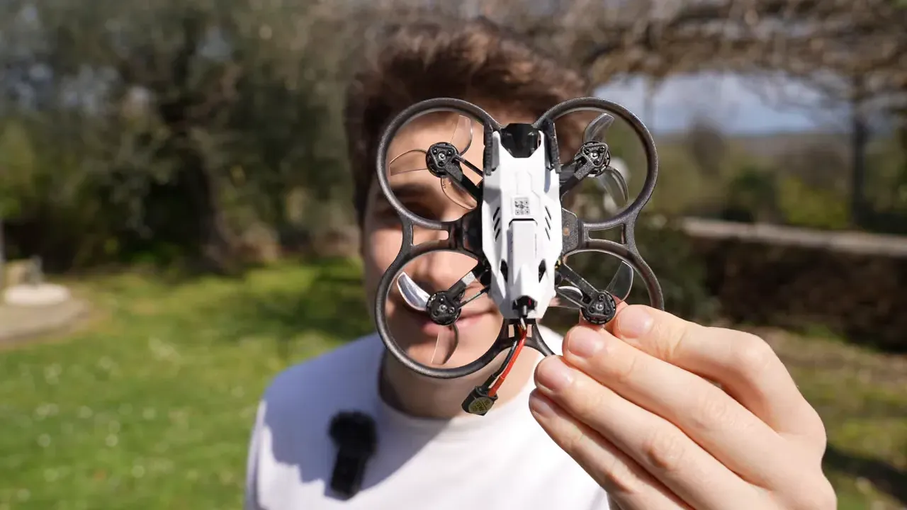 Hand holding the Oxbot Lumo18 tinywhoop outdoors with the front quad visible