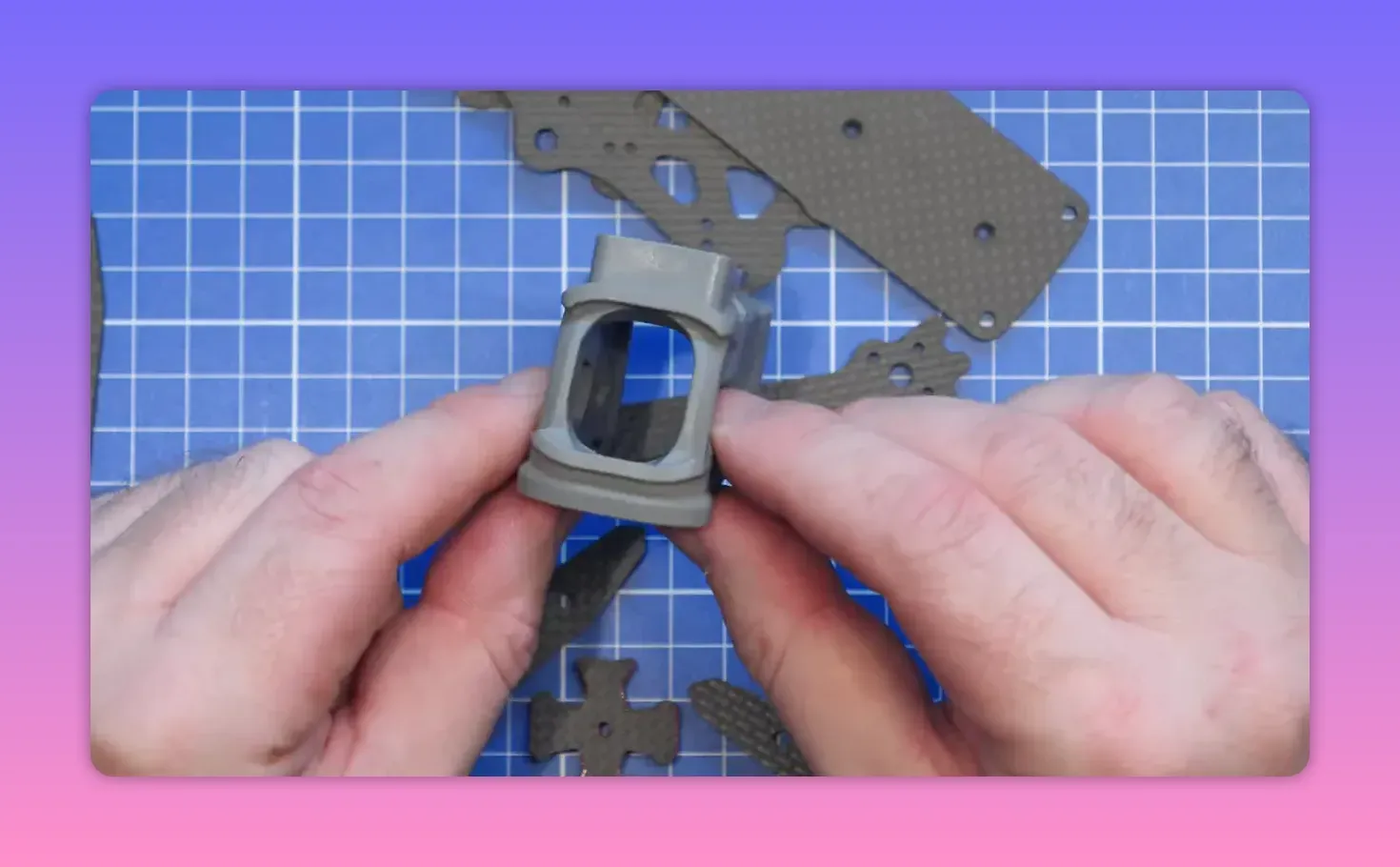 Hands positioning the ERA Mini moulded nylon front camera cage on a workbench