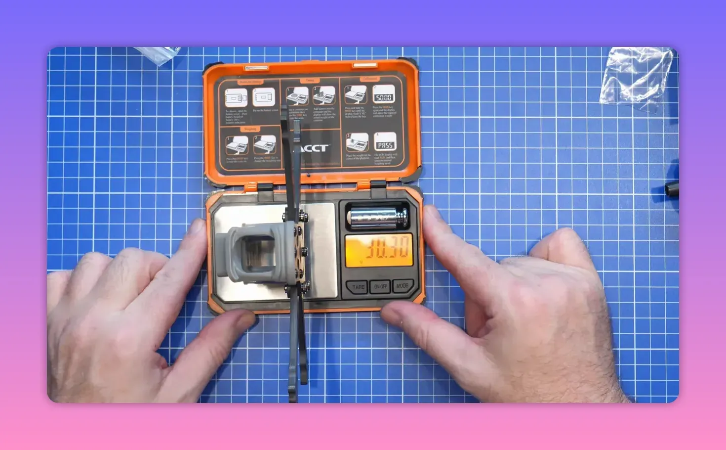 ERA Mini on a digital scale with hands adjusting the scale display on a blue cutting mat