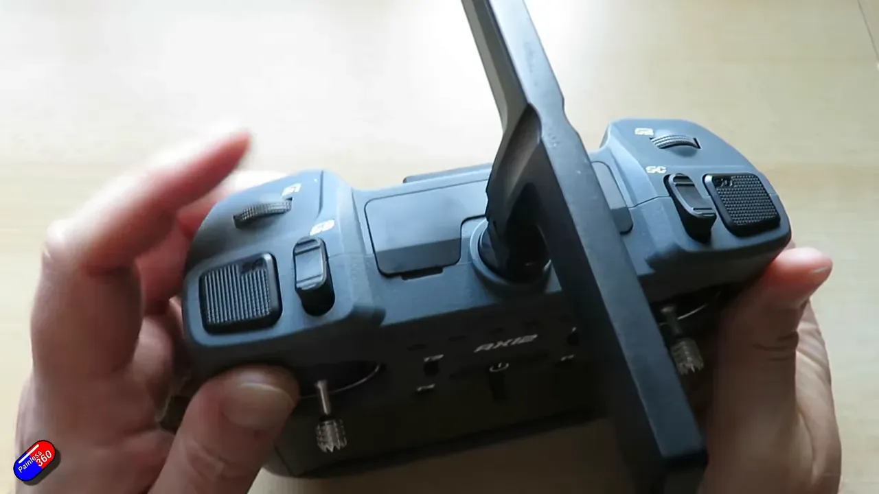 RadioMaster AX12 front view with gimbals, switches and detented roller visible while hands demonstrate controls