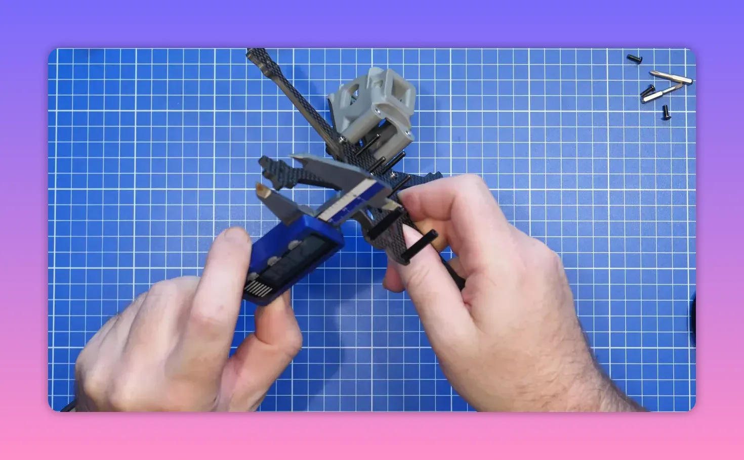 Hands positioning the FpV ERA Mini frame and front-end hardware on a blue cutting mat