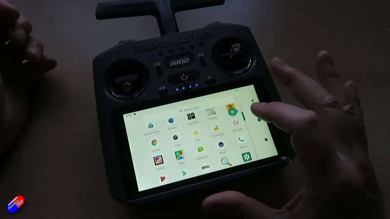 RadioMaster AX12 handheld radio displaying the Android app drawer on the touchscreen with a hand selecting an icon