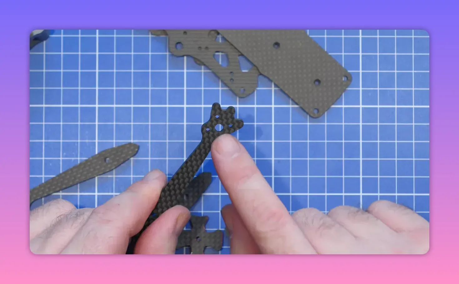 Hands positioning ERA Mini carbon frame front arms on a blue cutting mat