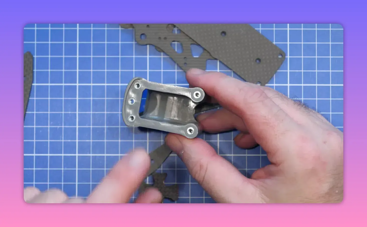 Hands positioning ERA Mini moulded front cage hardware on a blue cutting mat