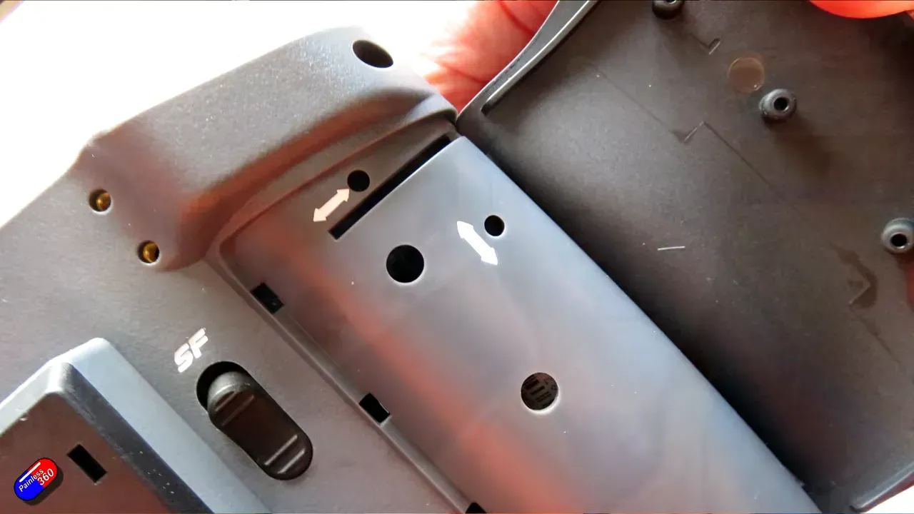 RadioMaster AX12 interior showing the battery compartment and joystick stow area with screw posts and directional arrows