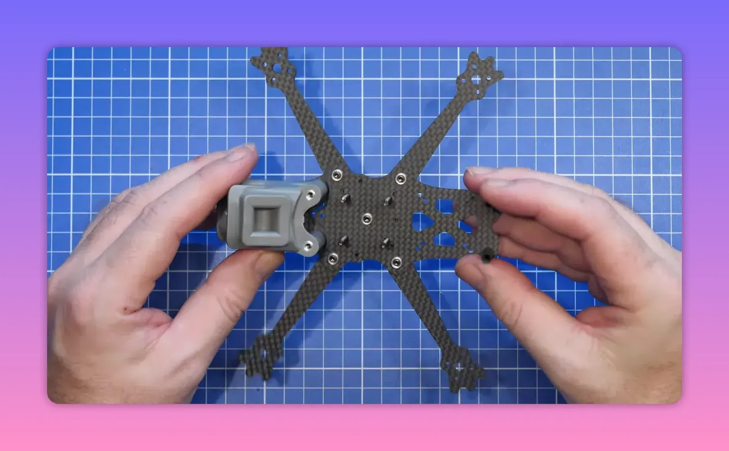 Hands holding the ERA Mini frame over a blue cutting mat during assembly