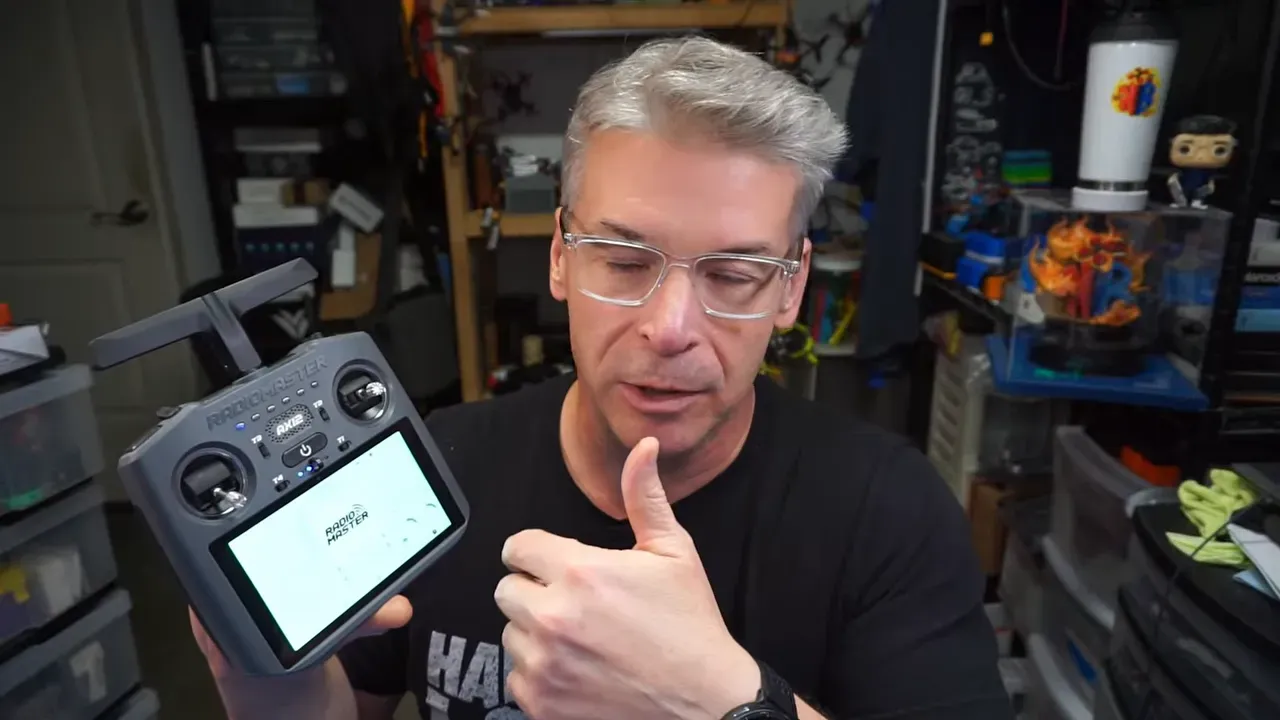 Nick Burns holding the RadioMaster AX12 transmitter with the Android tablet screen visible in a workshop