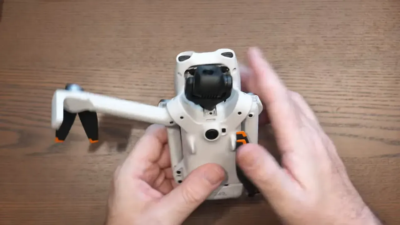 Hands holding the DJI Lito 1 drone as it is unpacked and inspected on a desk