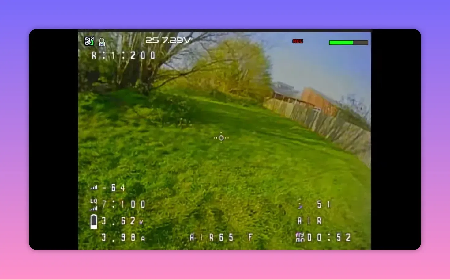 Analogue FPV HUD feed from the BetaFPV Air65 II over a grassy yard with trees and fence in view