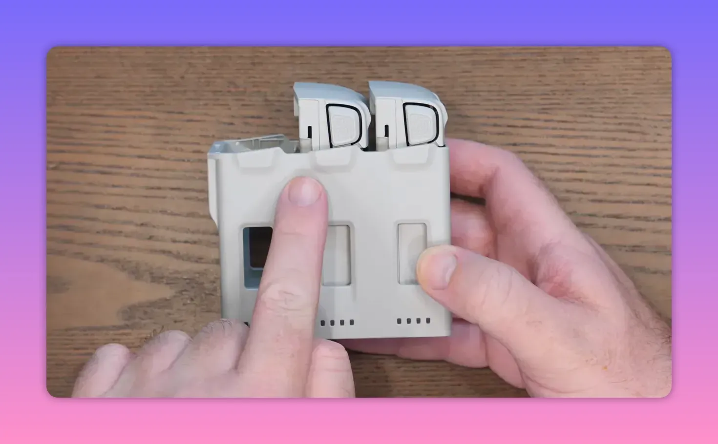 Hands holding the DJI Lito X1 Fly More charging hub case on a wooden table, showing the front ports and indicator holes