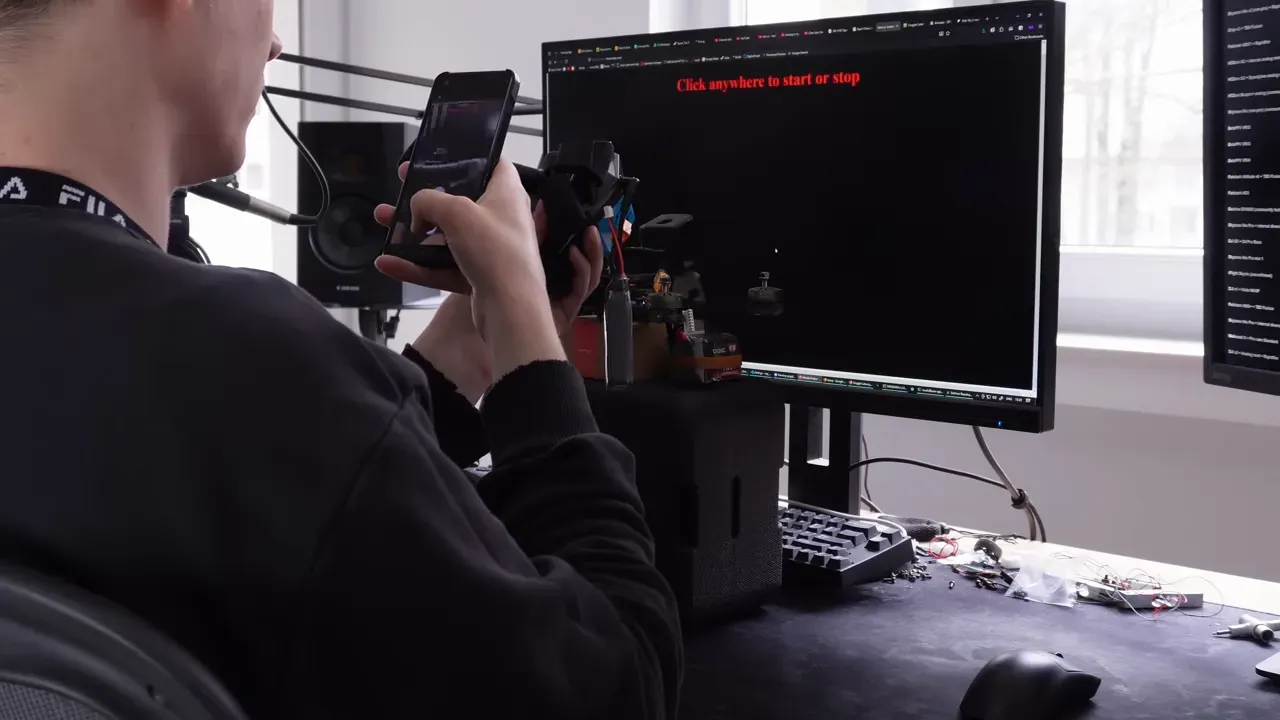 Pilot pointing a quad at a latency tester while recording the monitor and goggles simultaneously