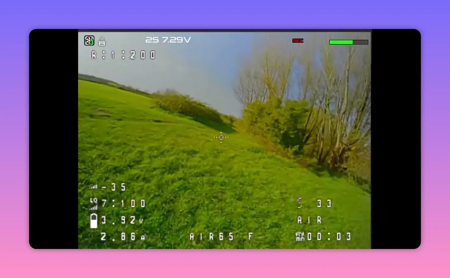 Analogue FPV view from the BetaFPV Air65 II freestyle with REC HUD overlay while flying over a grassy slope
