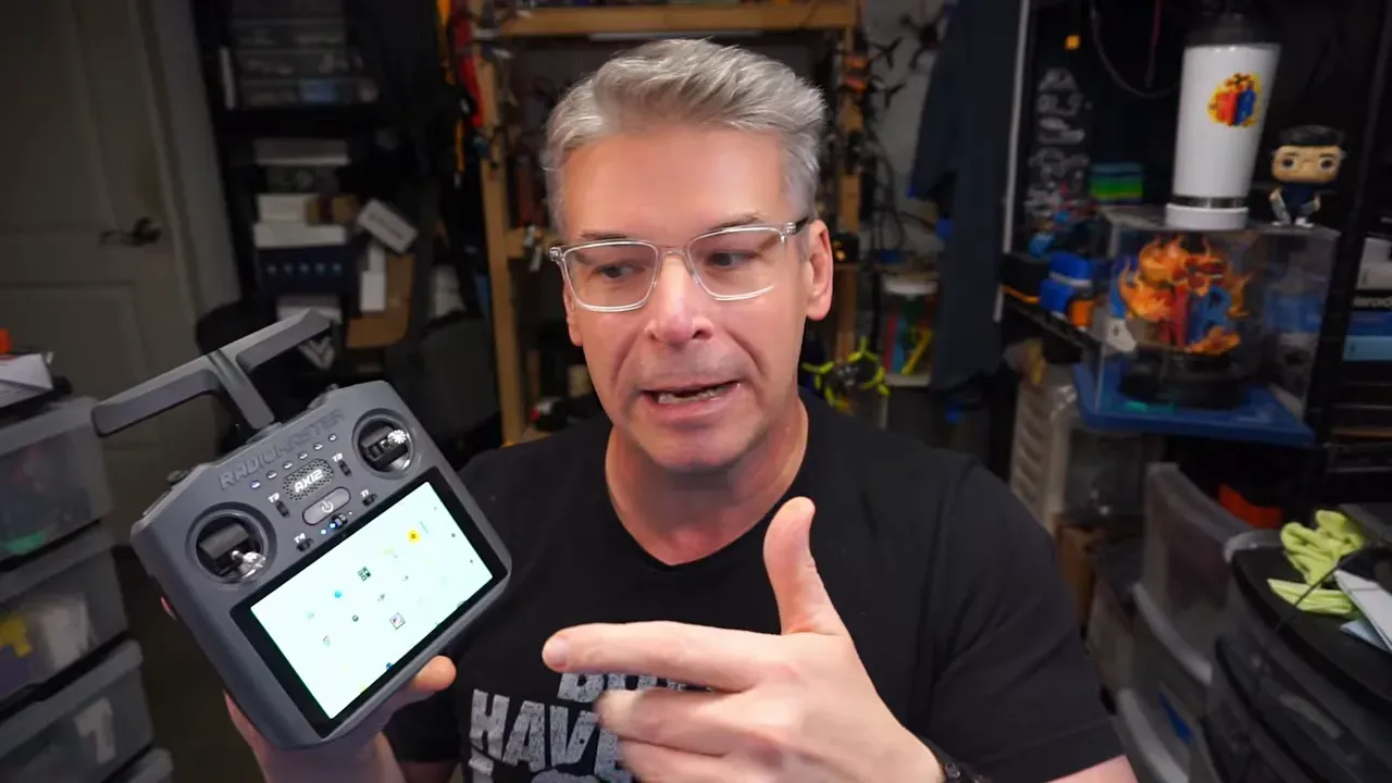 Nick Burns talking in a workshop while holding the RadioMaster AX12 transmitter with the built-in screen visible