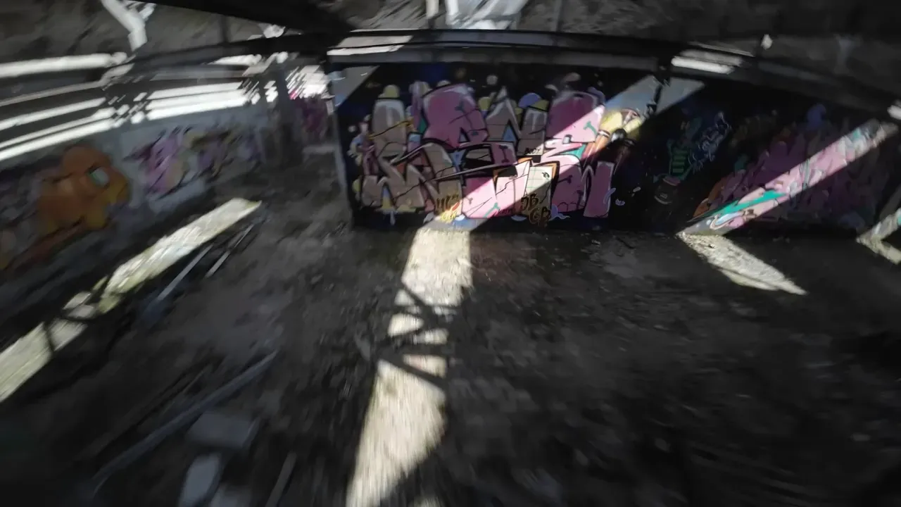 FPV camera view racing forward down a graffiti-covered corridor