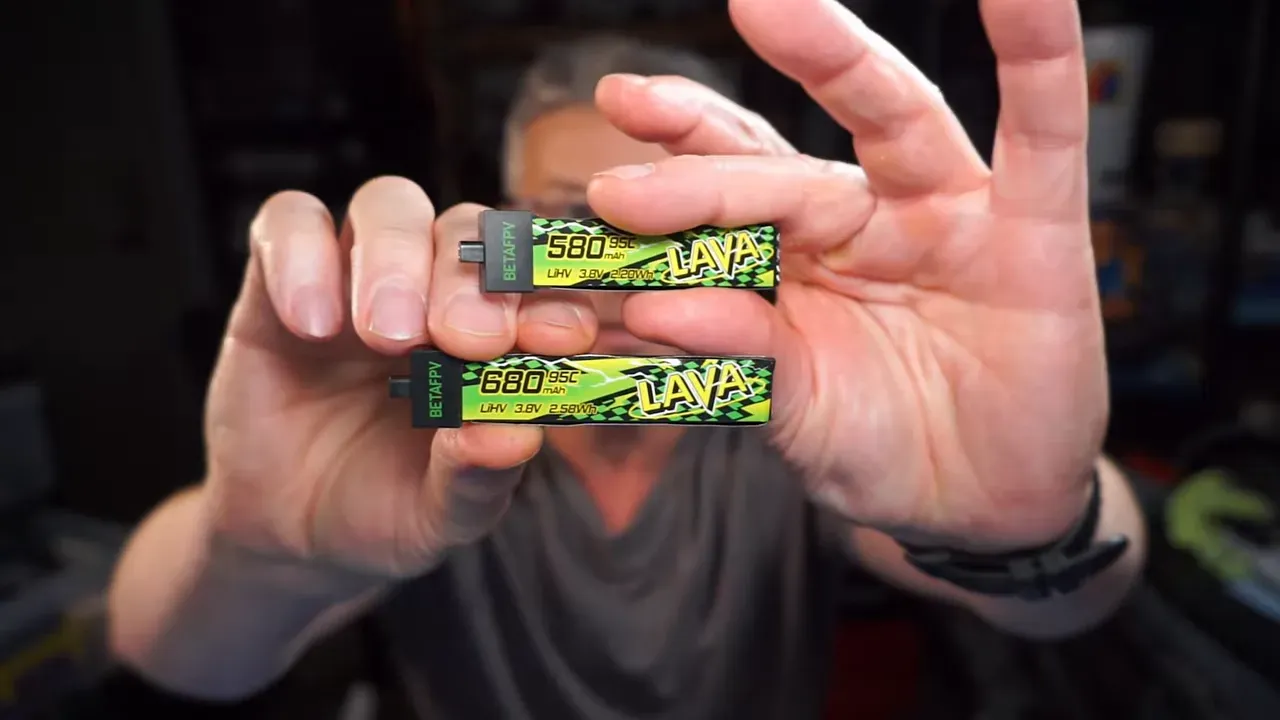 Three small green labelled batteries held in hand for size comparison