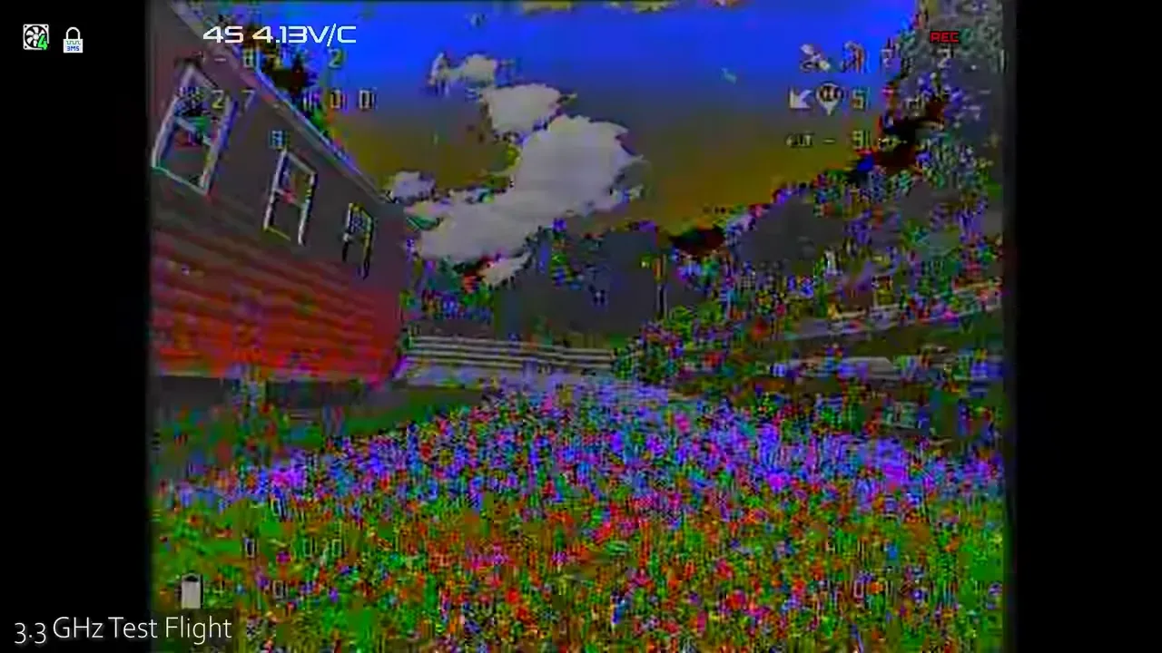 3.3 GHz DVR frame with visible breakup and heavy colour distortion near a road and open grass