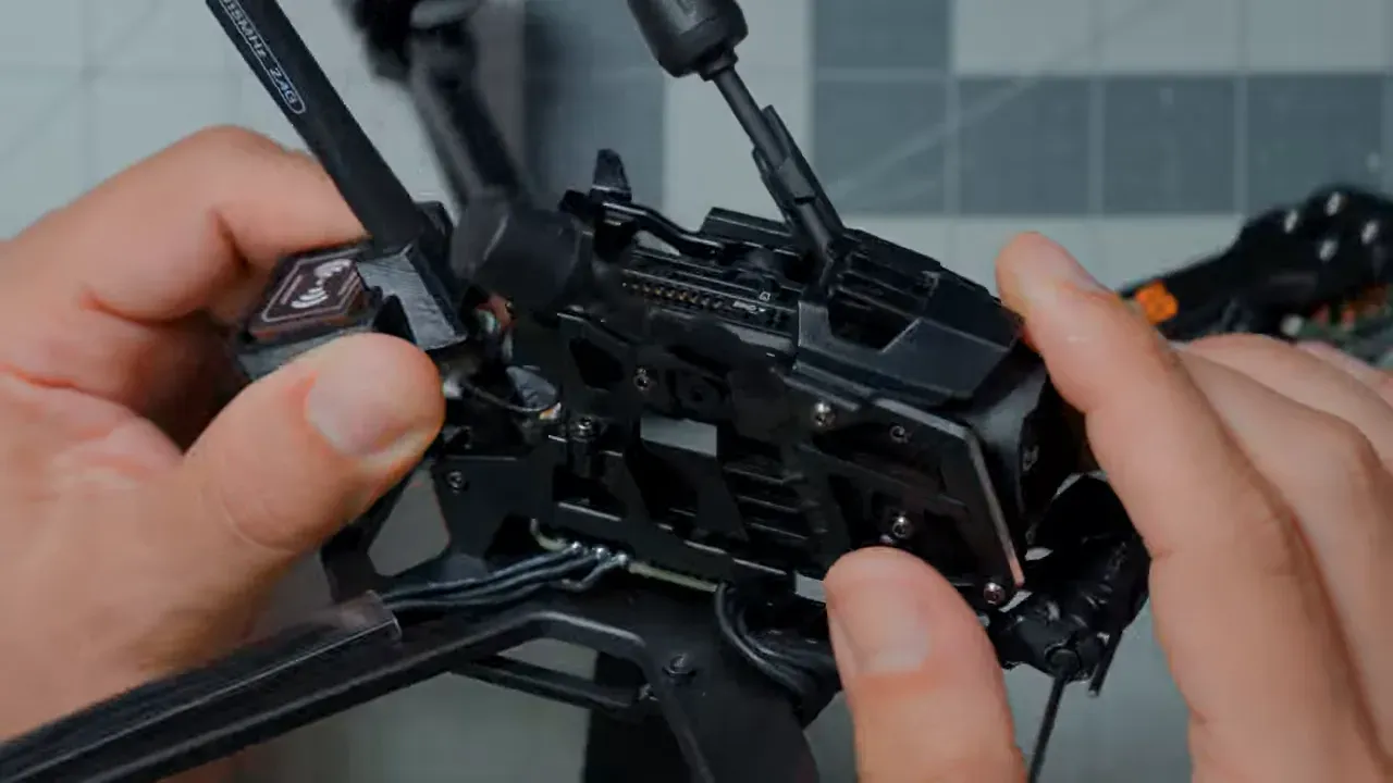 Hands removing the modular camera and video transmitter cage from the drone