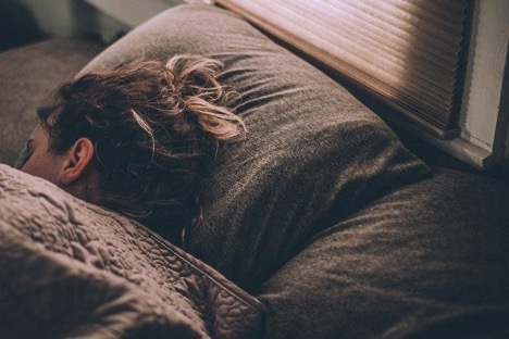 A woman sleeping under blankets with her head on the pillow. 